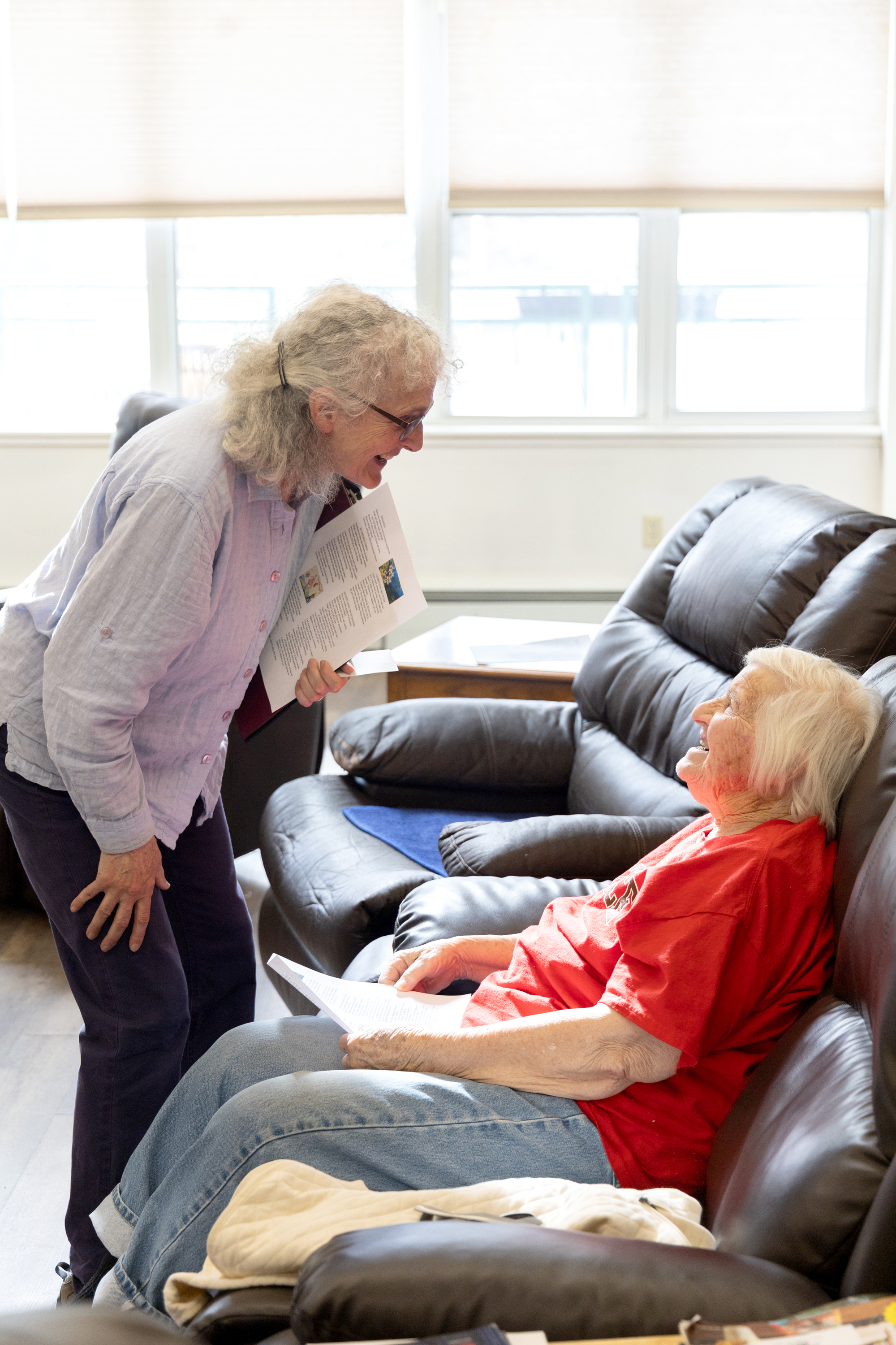 woman leaning over to talk to seated older woman